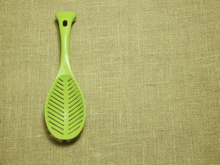 green plastic ladle on sackcloth woven background