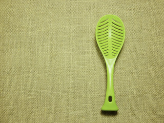 green plastic ladle on sackcloth woven background