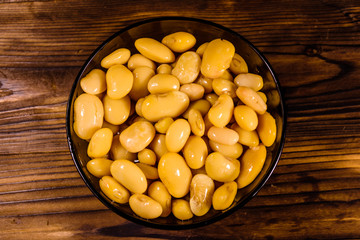 White marinated haricot beans in glass bowl on a wooden table. Top view