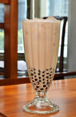 Milk tea with pearls on wooden table.