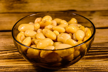 White marinated haricot beans in glass bowl on a wooden table