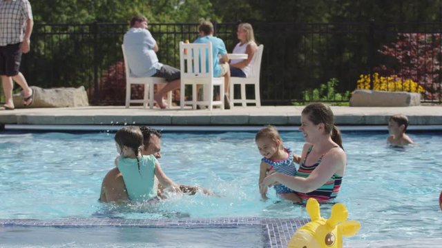 Family playing and splashing in backyard pool