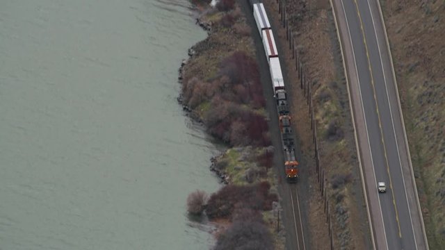 Aerial view of train moving down tracks parallel to roadway