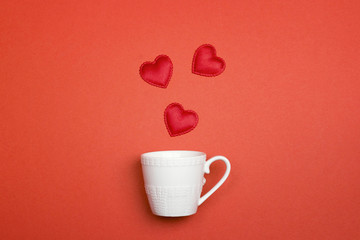 Coffee cup with Valentine hearts on red background.Top view.