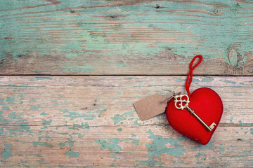 Red heart with antique key on old painted wooden boards. Space for text.