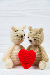 Couple teddy bear with red heart crochet knitting handmade on white wooden table, love and valentine concept.