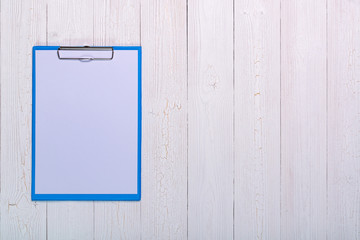 clipboard with blank white paper sheet on wood table top view with copy space.