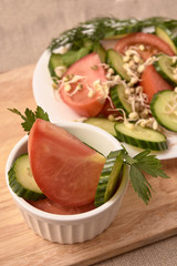 Tomato and cucumber. White plate. Sprouted beans. Fresh salad