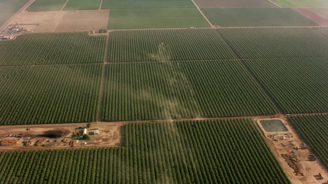 California circa-2017, Aerial shot of orchards with tractors making dust.  Shot with Cineflex and RED Epic-W Helium. 