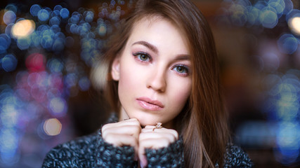 Portrait of beautiful young sad girl on the background of the winter night Christmas lights