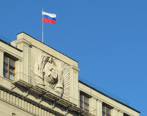 Fototapeta na wymiar Russian flag flew over the building of the State Duma against the blue sky