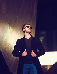 Handsome confident male model in elegant coat standing outdoors