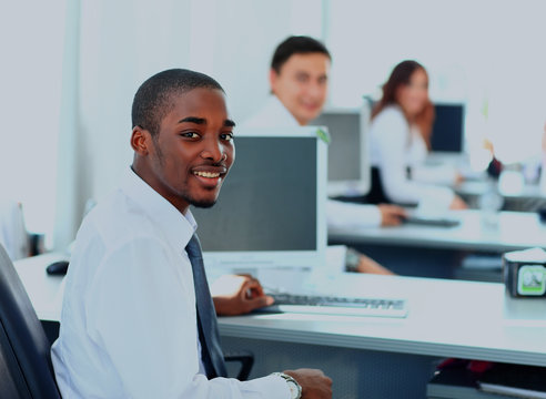 Portrait of a happy African American entrepreneur displaying computer laptop in office