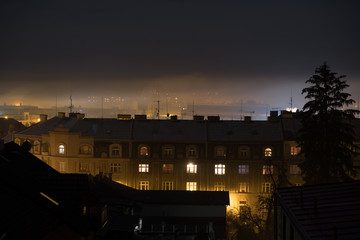 Fototapeta na wymiar night setting upon old buildings on a foggy day