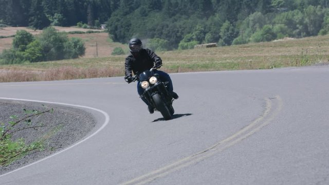 Tracking shot of man riding motorcycle on country road