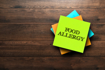Food Allergy, the phrase is written on multi-colored stickers, on a brown wooden background.