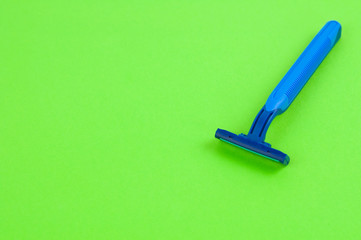 Single new blue plastic disposable razor with two blades on blank green paper