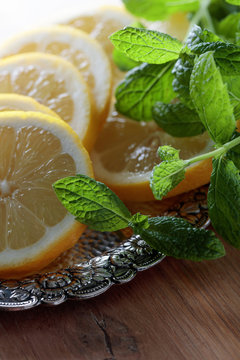 Lemon slices with mint leaves in old silver dish.