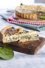 homemade pie with spinach and cheese, on a white wooden background. a serving of cake.