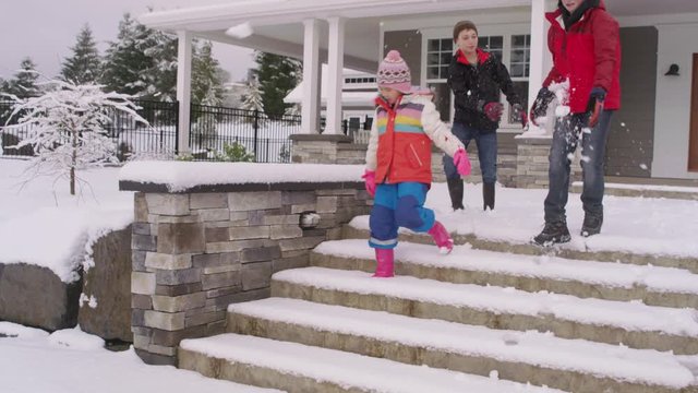 Three kids walking down snowy steps by home in winter