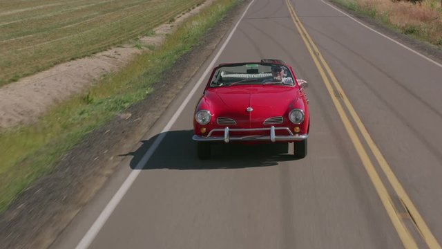 Tracking Shot Of Man Driving Classic Convertible Car On Country Road.  Fully Released For Commercial Use.