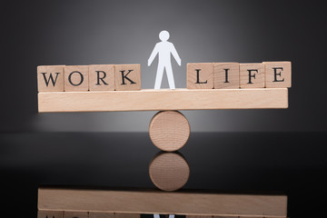 Human Figure Balancing Between Work And Life On Seesaw