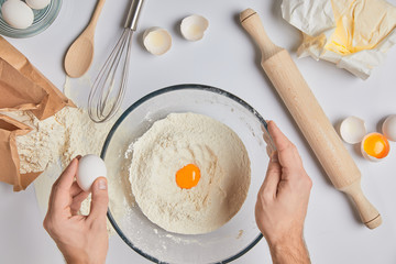 cropped image of chef adding eggs to flour