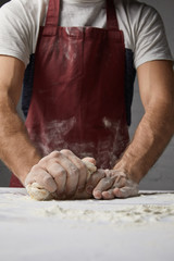 cropped image of chef kneading dough on table in kitchen