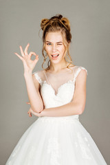 young bride showing okay hand sign gesture, on gray background.