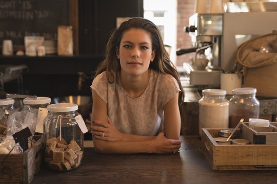 Portrait of waitress standing at counter in coffee shop