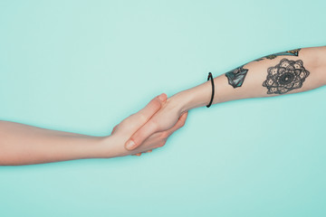 cropped shot of women shaking hands isolated on turquoise