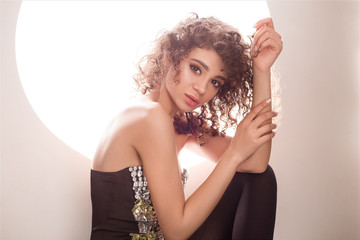 An amazing luxury woman sitting on the floor and posing in alluring clothes.