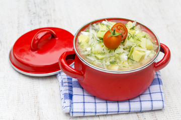 Red saucepan with okroshka - traditional summer soup in Ukraine, Belarus and Russia. Close up