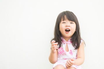 Happy Little asian girl in chinese traditional dress and eating chocolate candy, outdoor shoot on white background.