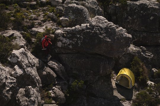 Hiker climbing down the rocks toward tent