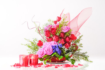 Romantic floral arrangement with red and pink roses with candles and symbols of Valentine's Day