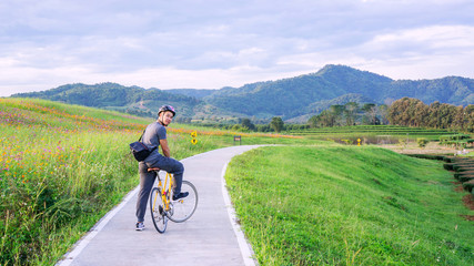 Fototapeta premium Men riding a bicycle near a lake at Singha park Chiang Rai, Thailand.