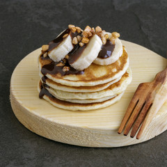 Pile of pancakes with banana and chocolate sauce.