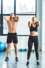 young couple stretching before workout in gym