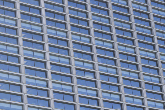 Background image of an office building facade full of glass windows.