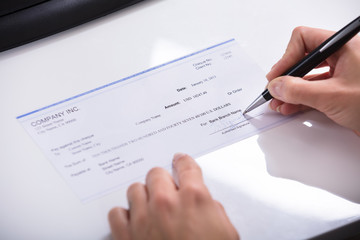 Person's Hand Signing Cheque