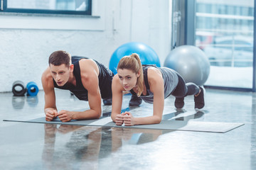 sporty young couple doing plank exercise in gym