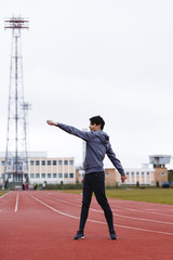 young sportsman makes exercises on a running track