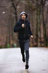 young man running in the park during the rain