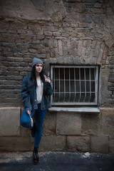 young woman leaning next to a window and old brick wall 