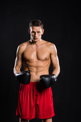 young muscular shirtless boxer looking at camera isolated on black