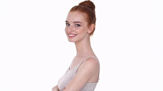 Pretty young cheerful redhead lady looking camera isolated over white wall background with arms crossed