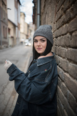 young woman leaning on brick wall in hipster clothes