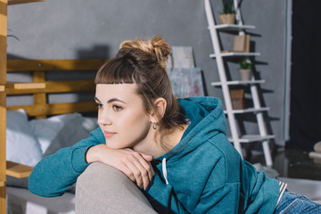 girl sitting on armchair in bedroom and looking away