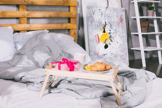 tray with breakfast and present box on blanket on bed